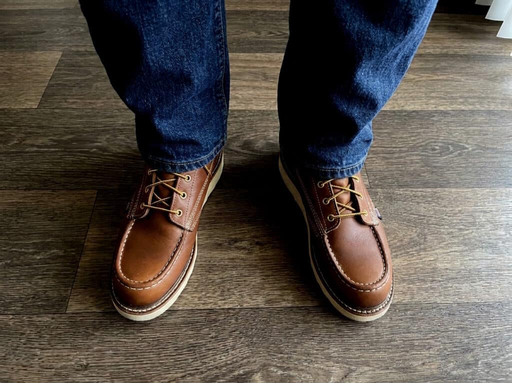 Front view of Thorogood American Heritage moc toe boots worn with jeans on a wood floor