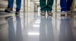 Brightly patterned children's shoes worn by kids in hospital corridor, reflecting on the shiny floor. Suitable for pediatric care, emphasizing comfort and style in kids' footwear.