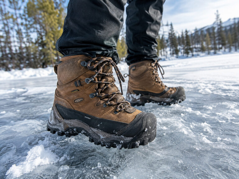 Close-up of rugged winter boots walking on icy snow, ideal for icy sidewalks and trails, showcasing traction and durability for winter conditions.