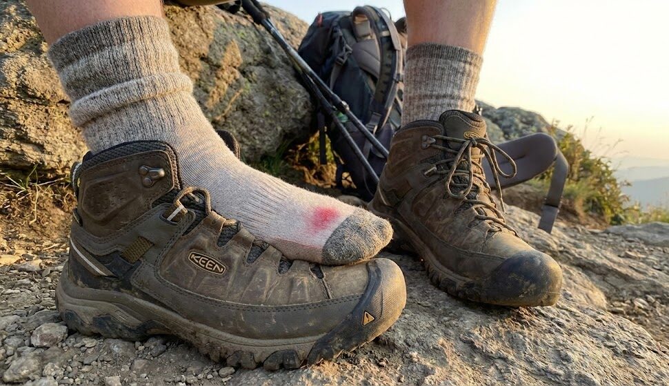 Hiker's boots and socks on rocky terrain.