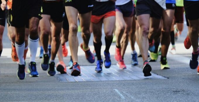 Group of marathon runners with athletic shoes and race bibs during a race event.