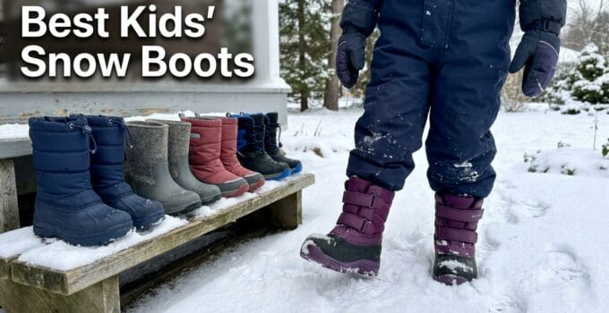 A child wearing purple snow boots standing in snow with a display of various kids' winter boots on a bench nearby.