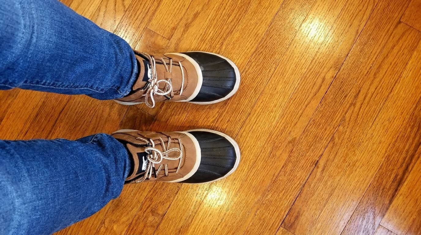 Sarah wearing the Sorel Women's Out N About IV Classic duck boots with jeans on a wood floor