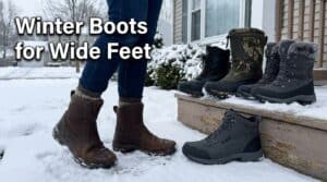 A person wearing winter boots standing on snow with three pairs of wide-fit winter boots displayed on a wooden step, suitable for wide feet in winter.